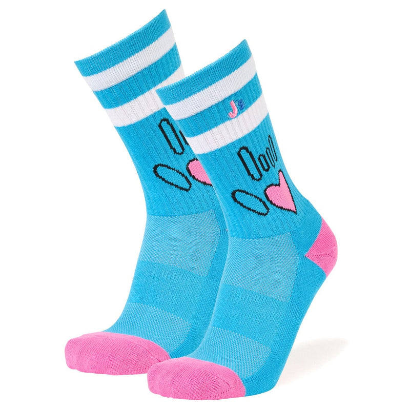 A pair of bright blue crew socks with white stripes at the top, featuring a cartoon face design with black outlines and pink hearts, finished with pink toes and heels, shown on a white background.