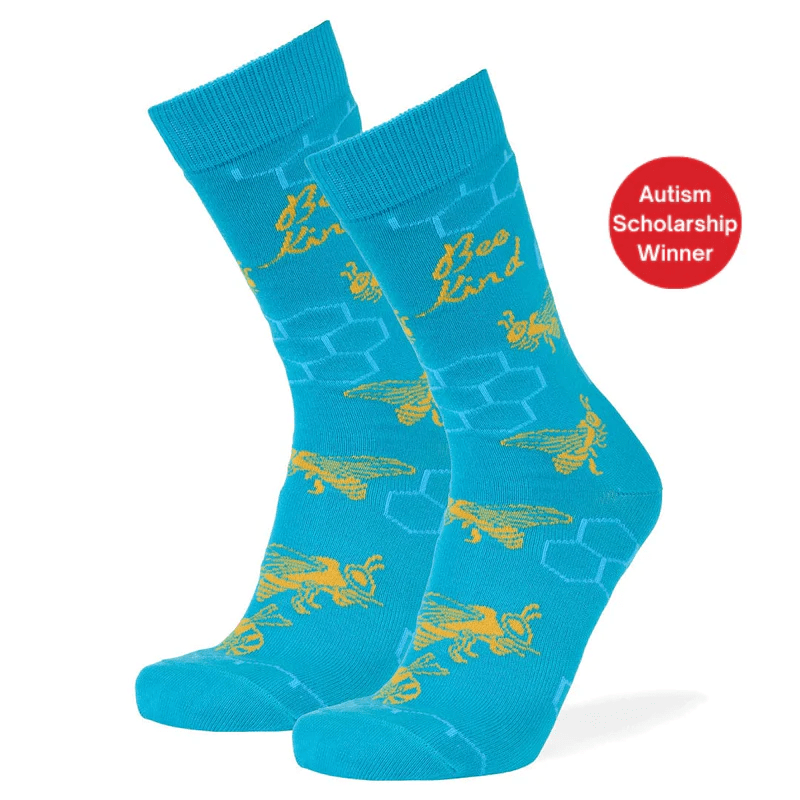 A pair of bright turquoise crew socks with a yellow bee and honeycomb pattern, shown on a white background with a red circular badge that reads 'Autism Scholarship Winner'.