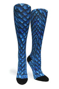 A pair of knee-high socks featuring a blue and black fish-scale pattern, with black toes and heels, shown against a plain white background.